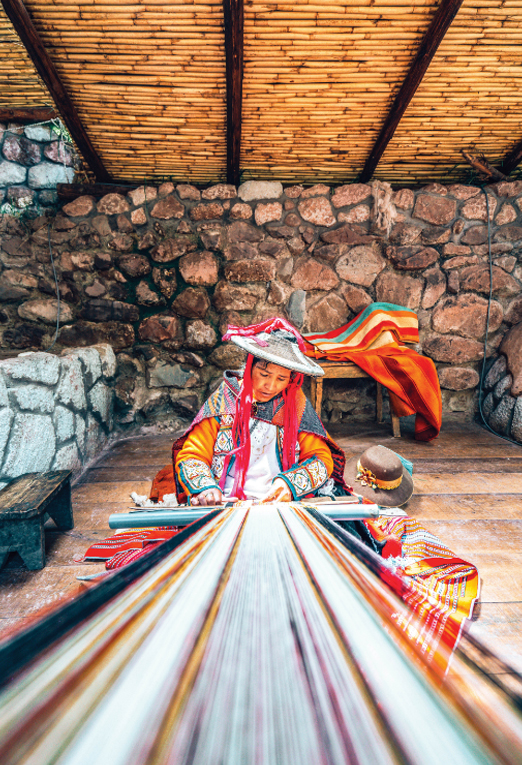 Our Philanthropic Partners Image Section A woman and her partner are weaving a large piece of cloth.