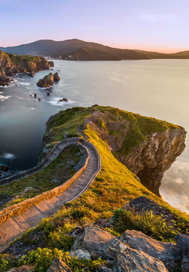 Landscape image of a mountain with a trail and an ocean