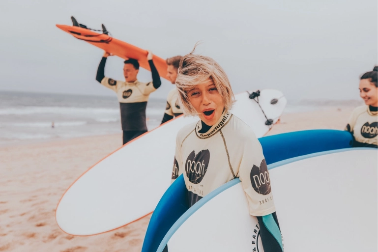 4 surfers walking on the beach