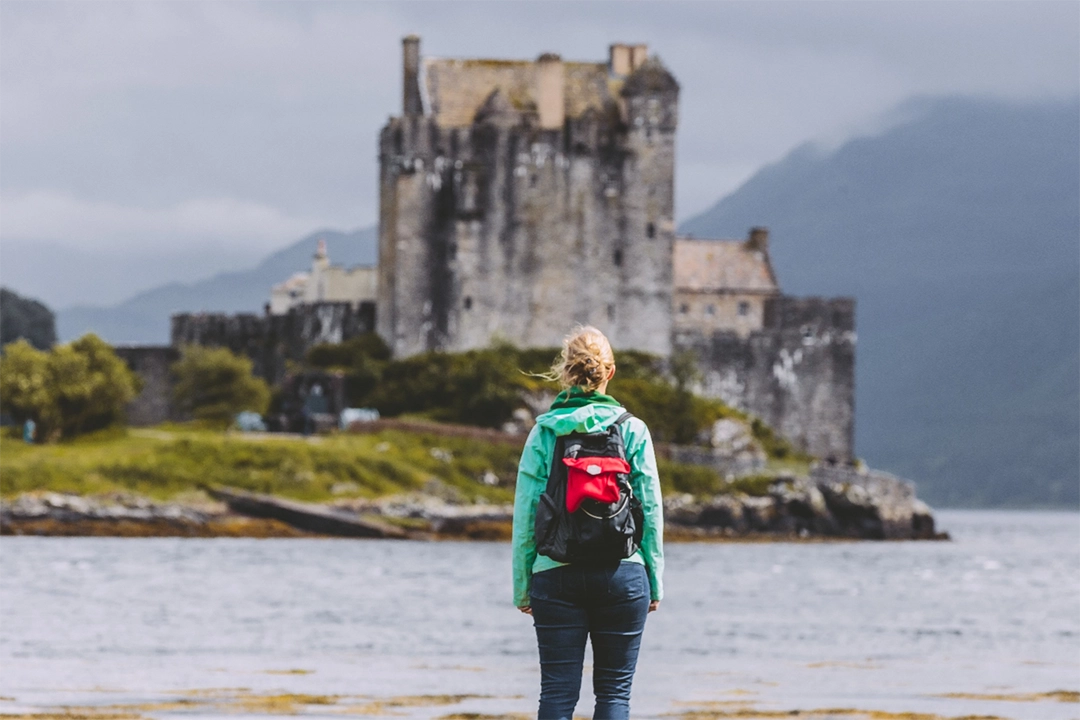 a woman looking out at a building across the waters