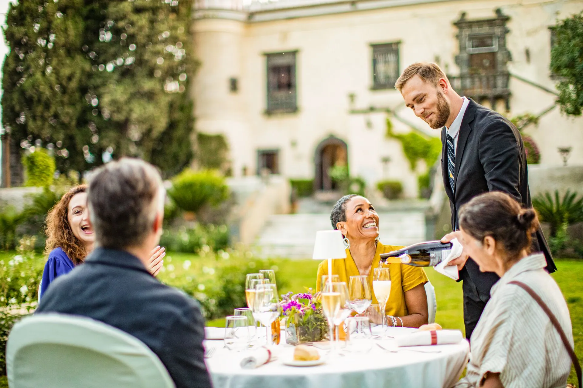 Man serving wine outside to a group of people 